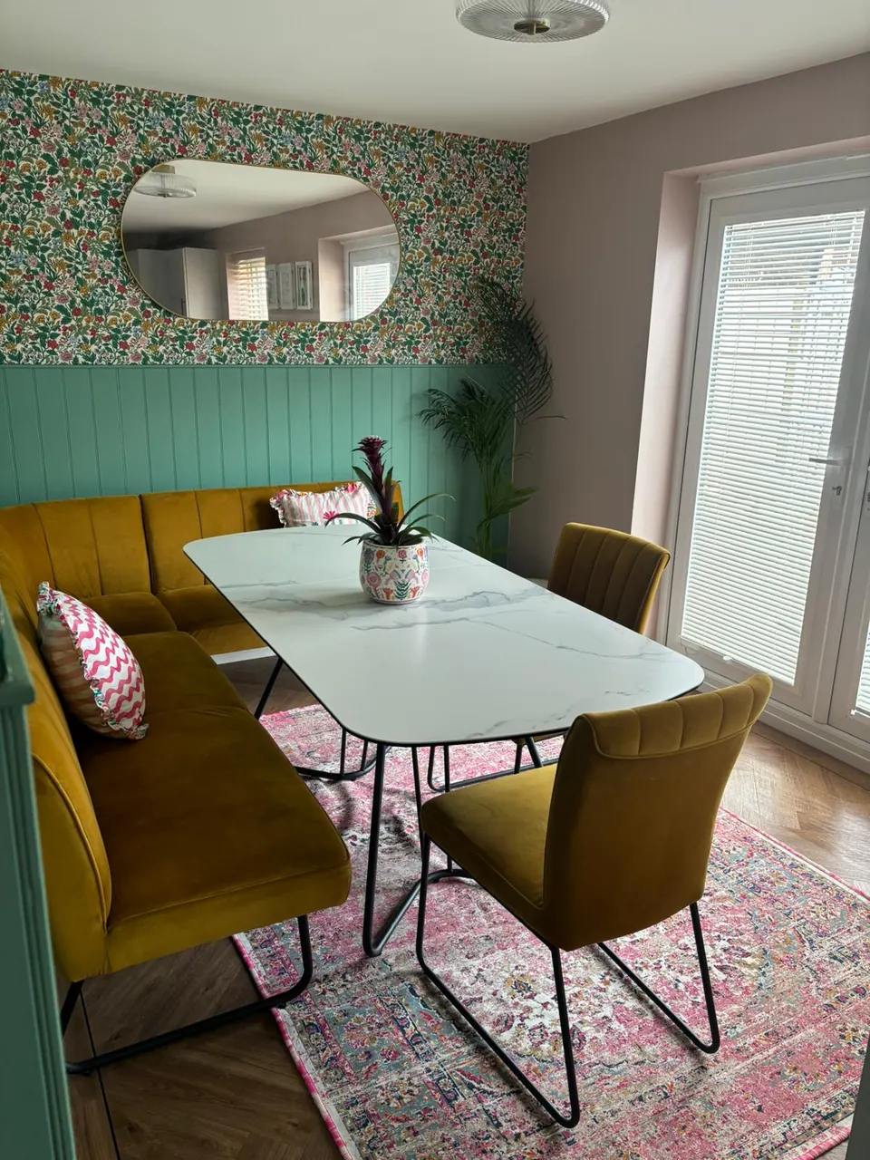 Clean residential dining area with styled seating, feature wall and hard flooring